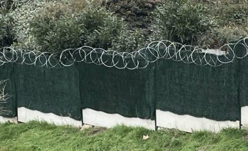 Photo de la pose d'une ronce défensive anti intrusion en fil tranchant sur clôture existante près de Paris dans le 75
